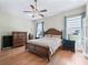 Comfortable bedroom with hardwood floors, ceiling fan, and natural light from the windows at 17787 Se 114Th Ave, Summerfield, FL 34491