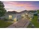 Exterior of a charming home with manicured landscaping and a beautiful sunset in the background at 17787 Se 114Th Ave, Summerfield, FL 34491