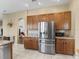 Open kitchen featuring stainless steel refrigerator, oak cabinets, and granite countertops at 17787 Se 114Th Ave, Summerfield, FL 34491