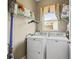 Compact laundry room with washer, dryer, overhead shelving, and a window at 17787 Se 114Th Ave, Summerfield, FL 34491