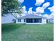 A sprawling backyard with grass, a screened-in patio, and white siding home at 1806 Estafana Way, The Villages, FL 32159