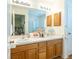A bathroom features double sinks and wood cabinetry at 1806 Estafana Way, The Villages, FL 32159