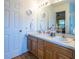 A bathroom features double sinks, wood cabinets and a bright mirror at 1806 Estafana Way, The Villages, FL 32159