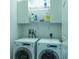 Bright laundry room featuring a washer, a dryer, cabinets, and wire shelving at 1806 Estafana Way, The Villages, FL 32159