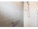 Modern bathroom featuring gray tiled walls, a handheld shower, and a built-in niche for storage at 2001 Dagenais Way, The Villages, FL 32163