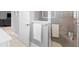 Bathroom with gray tiled walk-in shower, white towels, and white door leading to living area at 2001 Dagenais Way, The Villages, FL 32163