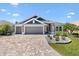 Charming home showcasing a three-car garage, paver driveway, manicured landscaping, and inviting curb appeal at 2001 Dagenais Way, The Villages, FL 32163