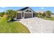 Beautiful home featuring a well-manicured lawn, palm trees, and a gray brick driveway leading to a two-car garage at 2001 Dagenais Way, The Villages, FL 32163
