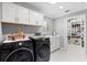 Well-lit laundry room featuring black front-loading machines and spacious shelving at 2001 Dagenais Way, The Villages, FL 32163