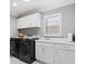 Laundry room boasting modern washer and dryer with white sink, countertop, and cabinets at 2001 Dagenais Way, The Villages, FL 32163