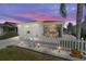 Charming exterior of a single-story home with a white picket fence and manicured lawn at dusk at 2063 Thornton Ter, The Villages, FL 32162