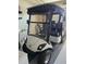 A close up view of a white Yamaha golf cart with black seats and a blue striped canopy in a garage at 2063 Thornton Ter, The Villages, FL 32162
