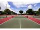 Several empty tennis courts display their green and red surfaces under a clear blue sky with green trees surrounding them at 2126 Burley Ave, Clermont, FL 34711