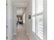 Inviting hallway with white trim, tile floors, shutters, leading to open-concept living space at 2129 Palm Tree Dr, Poinciana, FL 34759