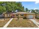 Charming single-story home with yellow paint, a red front door, an attached garage, and a well-manicured lawn at 2252 Kent Rd, Deltona, FL 32738