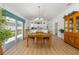 Dining room with wood floors leading to a bright kitchen and a sliding glass door with natural light at 2403 Muirwood Pl, The Villages, FL 32162