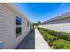 Landscaped view of the side of the home showing the exterior, walkway, and green bushes at 2403 Muirwood Pl, The Villages, FL 32162