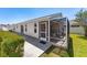 Exterior view of the home highlighting the screened-in patio, yard, and surrounding landscaping at 2403 Muirwood Pl, The Villages, FL 32162