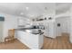 Bright kitchen with white cabinets, breakfast bar, and wood-look flooring, complemented by recessed lighting and an open layout at 2403 Muirwood Pl, The Villages, FL 32162
