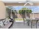 Screened-in patio with outdoor seating, table, chairs, and view of the backyard and garden at 2403 Muirwood Pl, The Villages, FL 32162