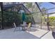 Covered patio with a table, chairs, umbrella, and a screen enclosure surrounded by lush greenery at 2482 Ansley Path, The Villages, FL 32162