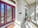 Elegant front entryway with a decorative glass door, a welcoming wreath, and a charming outdoor seating area at 27027 Old English Ct, Leesburg, FL 34748