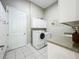 Functional laundry room featuring a modern washer and dryer, ample cabinetry, and tiled flooring at 27027 Old English Ct, Leesburg, FL 34748