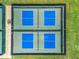 Aerial view of the community pickleball courts featuring two vibrant blue courts, a green border, and fencing at 27027 Old English Ct, Leesburg, FL 34748