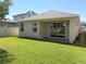 The rear exterior shows the yard with the sliding glass door of the patio, a window, and the green lawn at 2721 Picasso Ct, Kissimmee, FL 34743