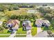 An aerial view of the home with green lawn and landscaping with a lake and wooded area nearby at 27510 Discover Ct, Leesburg, FL 34748