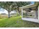 Exterior view of an enclosed sunroom from the backyard with lush green grass and mature trees at 27510 Discover Ct, Leesburg, FL 34748