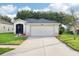 Two-car garage with long driveway and manicured landscaping at 27510 Discover Ct, Leesburg, FL 34748