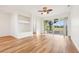 Bright living room with hardwood floors, built in wall shelf, and sliding glass doors to lanai at 27510 Discover Ct, Leesburg, FL 34748