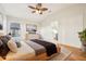 Staged bedroom with wood floors, ceiling fan, and a view of an ensuite bathroom at 27510 Discover Ct, Leesburg, FL 34748