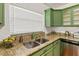 Kitchen sink area featuring granite counters, stainless steel sink, and green cabinets at 306 N Clayton St, Mount Dora, FL 32757