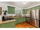 Well-appointed kitchen with granite counters, stainless appliances, and unique green cabinetry at 306 N Clayton St, Mount Dora, FL 32757