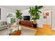 Modern living room featuring hardwood floors, tropical plants, a sleek media console, and an open doorway at 306 N Clayton St, Mount Dora, FL 32757