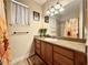 Bathroom with a long vanity, large mirror, flower-themed decor, and tiled shower at 31728 Nutmeg Ave, Eustis, FL 32736