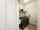 A well-organized laundry room featuring a washer, dryer, shelving, and tile flooring at 31728 Nutmeg Ave, Eustis, FL 32736
