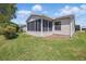 Back exterior view of the house with sunroom, siding, green lawn, and blue sky at 3294 Shelby St, The Villages, FL 32162