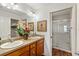 Bathroom featuring double sinks, wood cabinets, and a glass-enclosed shower at 3396 Greenacres Ter, The Villages, FL 32163