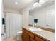 Bright bathroom featuring a single sink vanity, large mirror, and a shower-tub combination with neutral finishes at 3396 Greenacres Ter, The Villages, FL 32163
