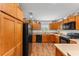 Bright kitchen featuring wood cabinets, black appliances, and wood-look flooring at 3396 Greenacres Ter, The Villages, FL 32163