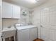 Functional laundry room with a utility sink, a white washer and dryer, and ample storage cabinets for convenience at 3396 Greenacres Ter, The Villages, FL 32163