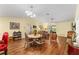 Bright living room with wood-look floors, dining area, and vaulted ceiling at 3396 Greenacres Ter, The Villages, FL 32163