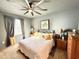 Well-lit bedroom with large bed, ceiling fan, window with curtains, and wood furniture at 34004 Sky Blossom Cir, Leesburg, FL 34788