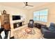Inviting living room with plush seating, ceiling fan, and a large window for natural light at 34004 Sky Blossom Cir, Leesburg, FL 34788