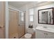 Bathroom featuring a glass door shower, white vanity with white sink, white toilet, and window at 34407 Island Dr, Leesburg, FL 34788