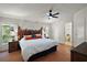Bright main bedroom featuring a decorative headboard, ceiling fan, two windows, and ensuite bathroom at 34407 Island Dr, Leesburg, FL 34788
