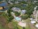 Aerial view showcasing community amenities: tennis courts, pools, clubhouse, lakes, and lush landscaping at 3723 Belle Rose Dr, Leesburg, FL 34748